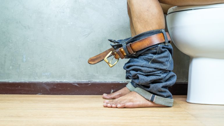 Mann sitzt auf der Toilette