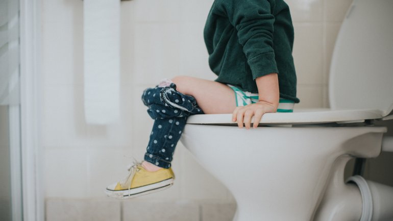 Kind sitzt auf der Toilette